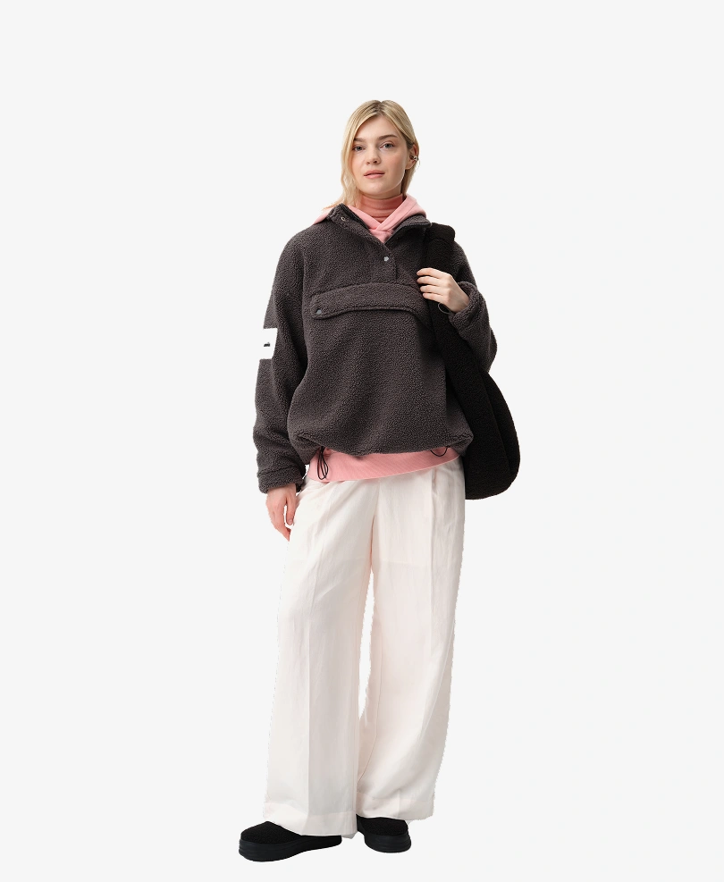 Modelka prezentuje stylizację lookbookową Kubota, na którą składają się: grafitowa damska bluza polarowa Cushy, czarna torba shopper z polaru i wodoodporne śniegowce Cushy. Zestaw z kolekcji jesień/zima 2025.