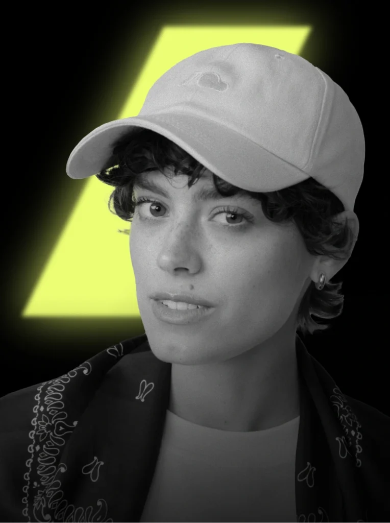 Zdjęcie lookbookowe prezentujące różową czapkę z daszkiem Cloud w cenie promocyjnej na Black Weeks. Fotografia modelki na ciemnym tle z kontrastowym, żółtym elementem graficznym będącym częścią logo Kuboty.