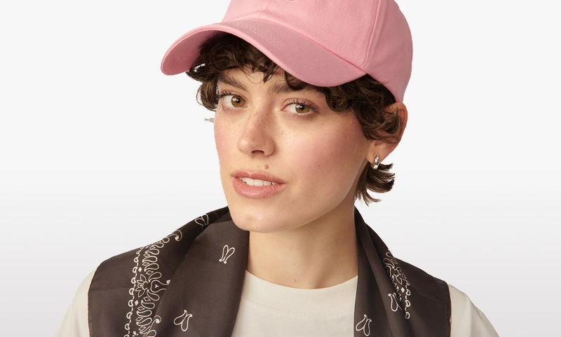 Baner kategorii Kobieta. Modelka nosząca różową czapkę z daszkiem od Kuboty.