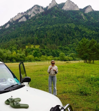 Zdjęcie @martynamik w górskiej scenerii. Na masce białego samochodu leżą klapki Kubota khaki.