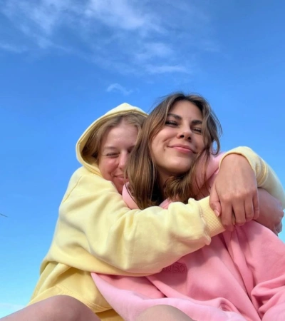 Zdjęcie @xigapas przedstawiające dwie osoby w pastelowych bluzach z kapturem Kubota na tle błękitnego nieba.