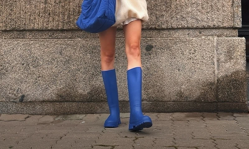 Baner kategorii festiwalowy look. Stylizacja z wysokimi, kobaltowymi kaloszami Kubota na tle kamiennego muru.
